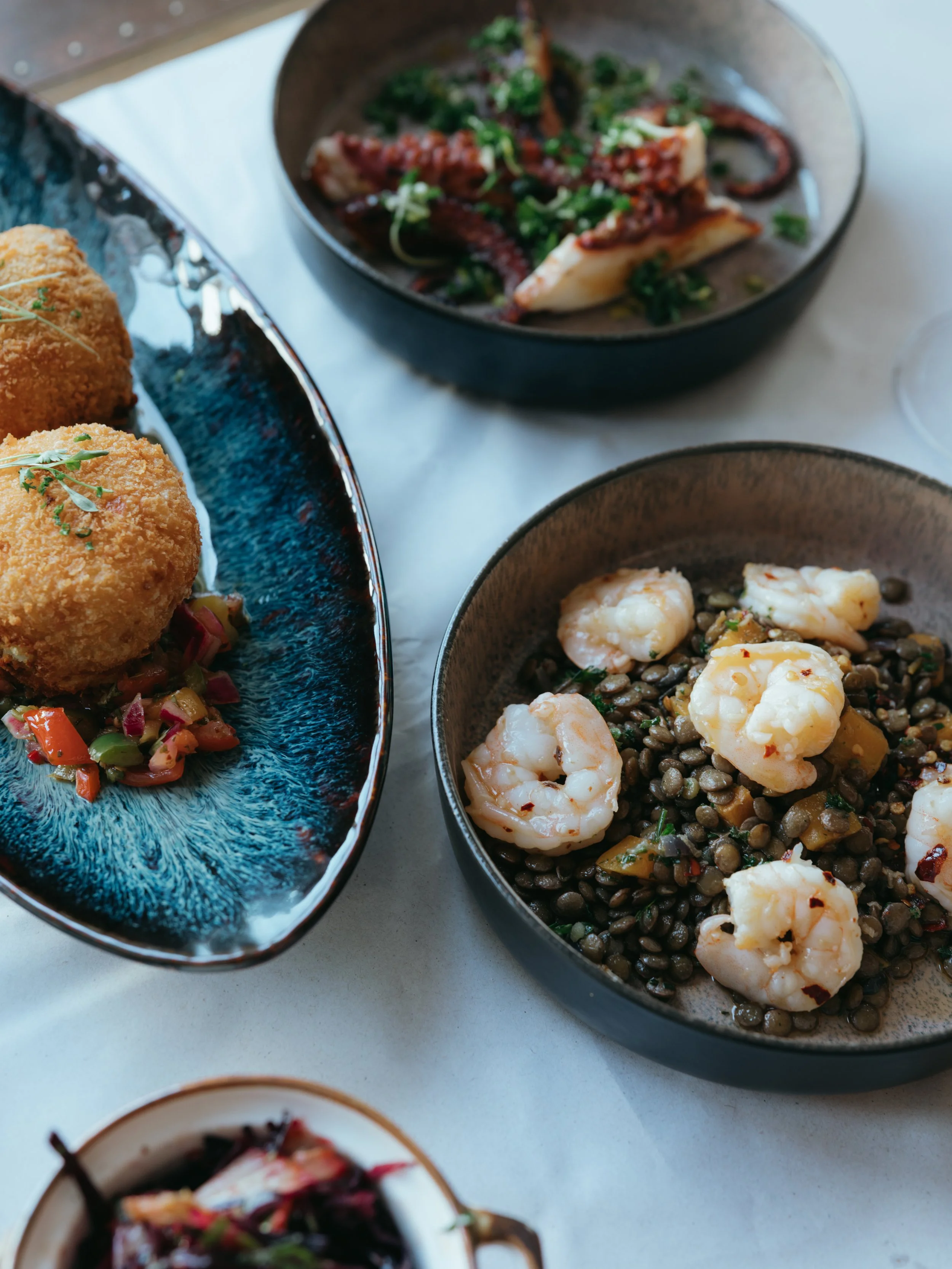 A display of food from our sharing menu, in this photo is succulent garlic prawns on a bed of puy lentils.