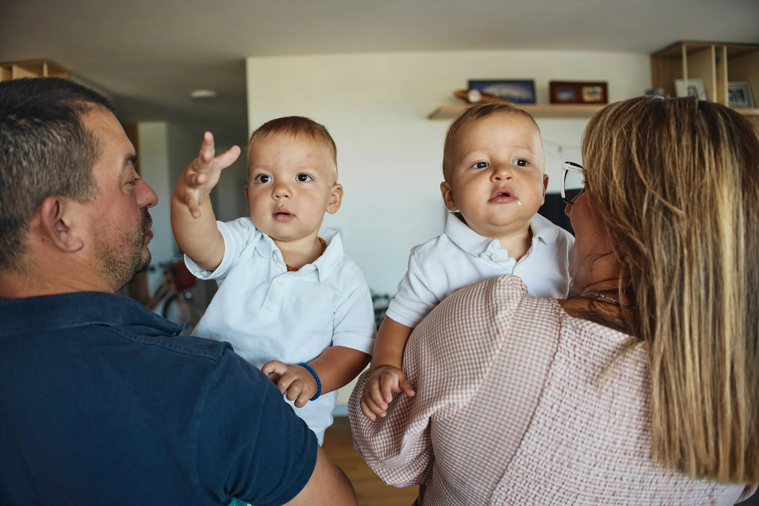 Young twins being held by a man and a woman.
