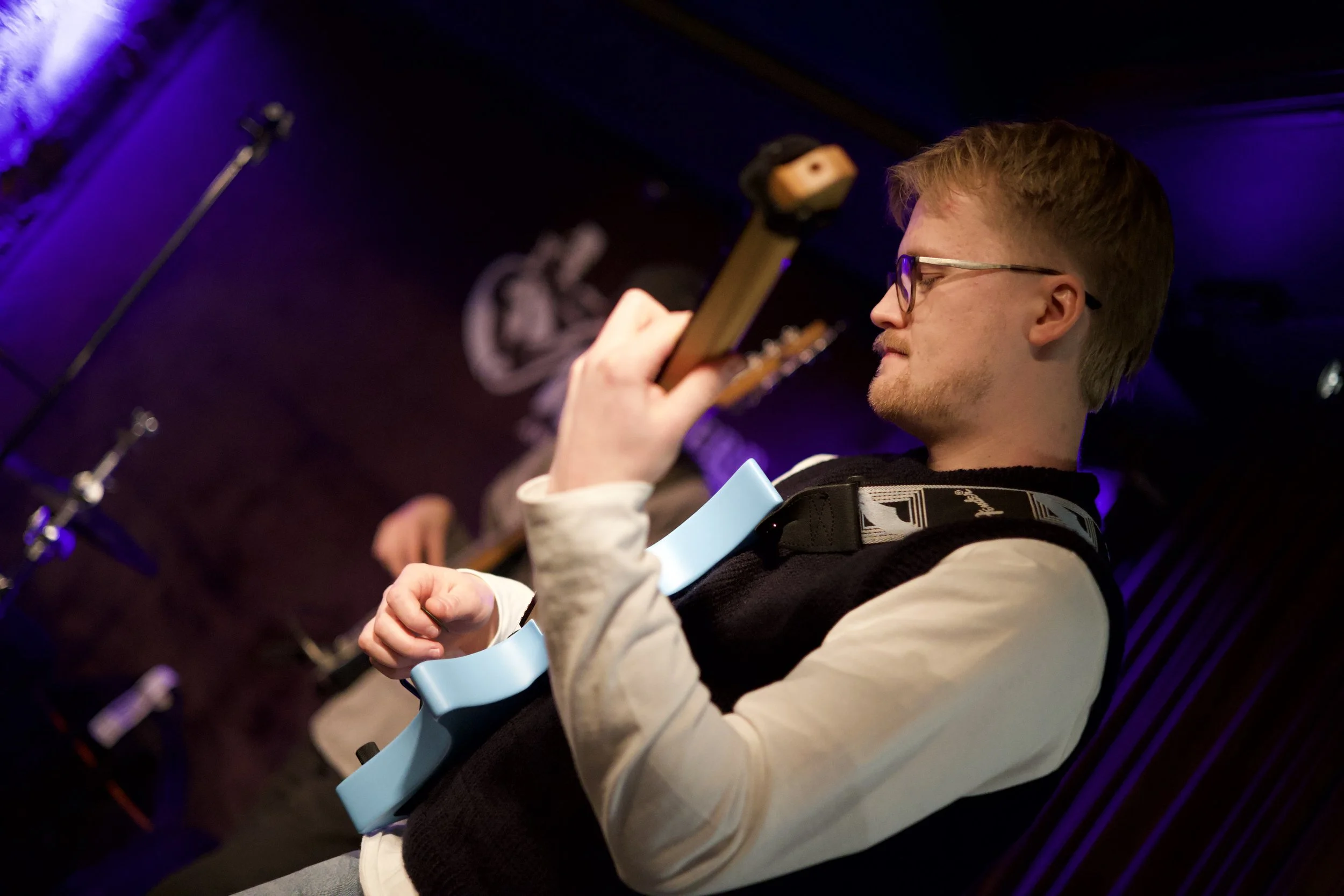 Gitarist spiller i blått og lilla scenelys.