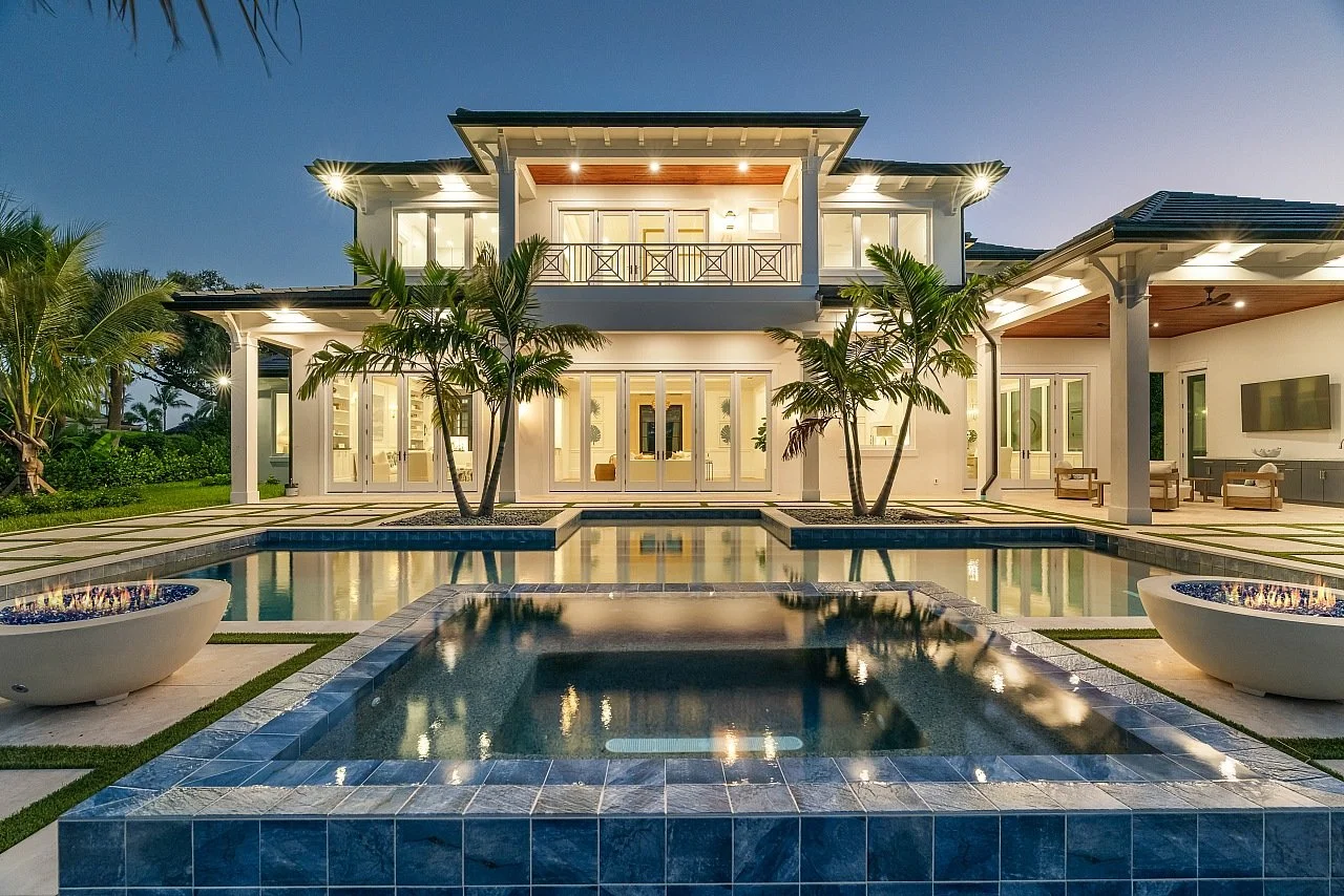 Luxury modern house with a swimming pool and palm trees, illuminated at night.
