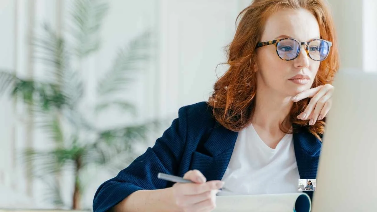 Woman at a computer listening and writing notes, representing fear-based motivation in coaching and choosing clarity over pressure