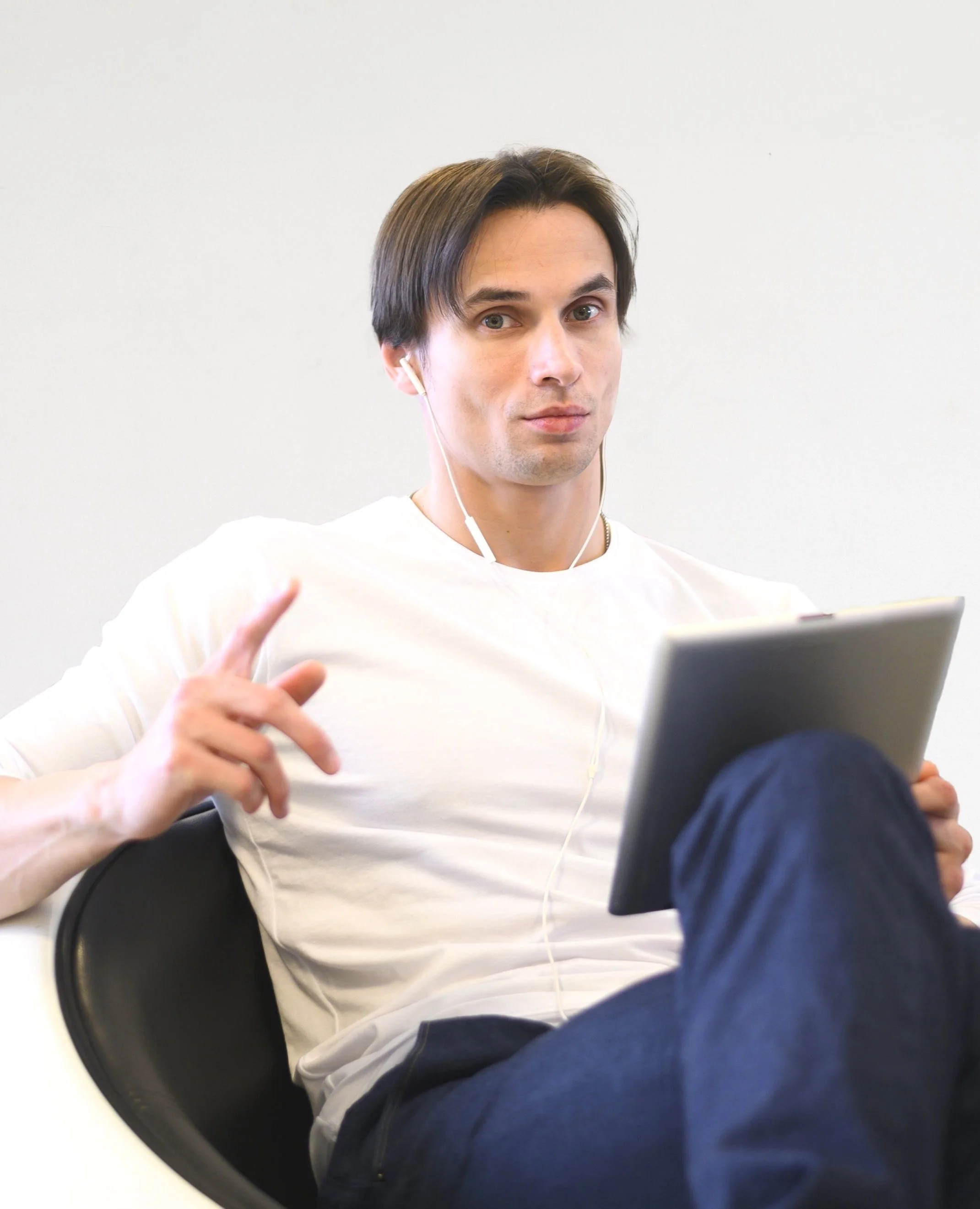 Man in white shirt with earphones holding a tablet