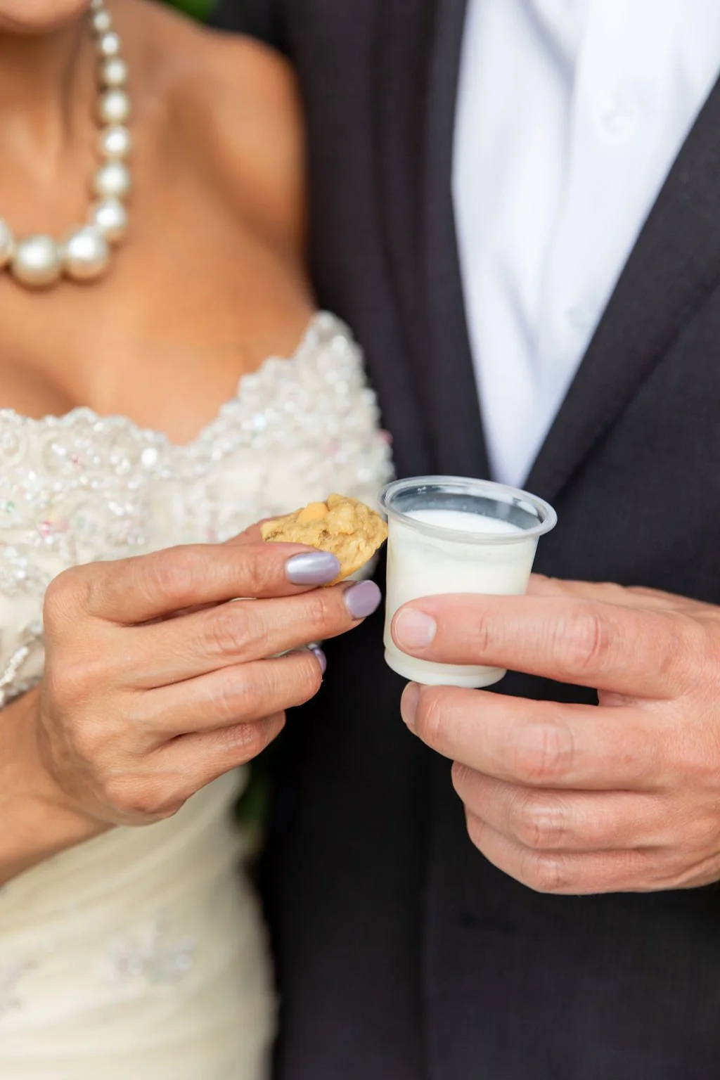Bride and groom holding tiny cookies & milk