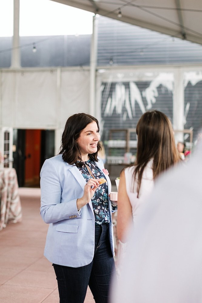 Two women talking at a networking event and eating cookies