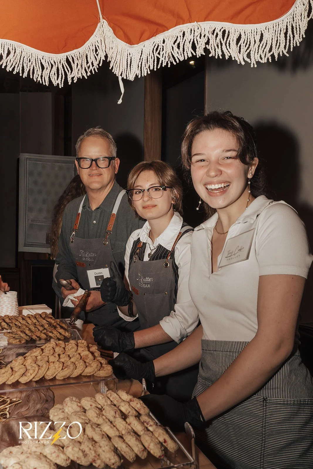 Three people serving cookies & ice cream, smiling