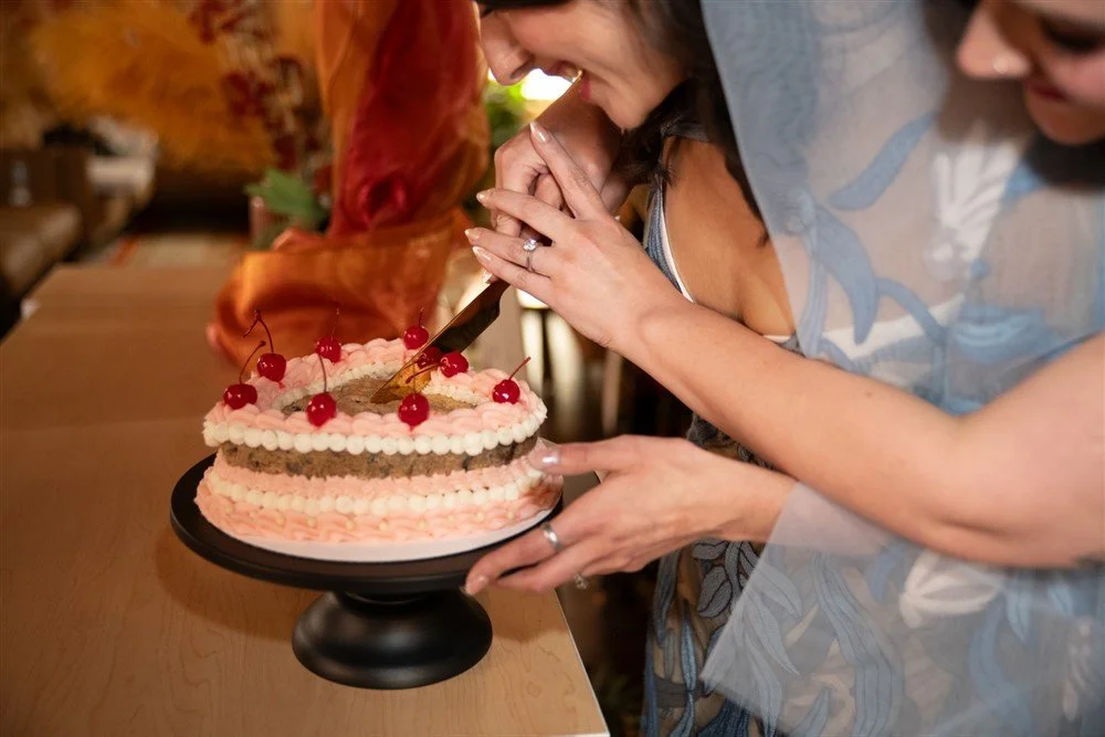 Close up of two brides cutting into an intricately decorated cookie cake