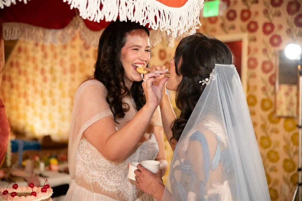 Two brides feeding each other cookies