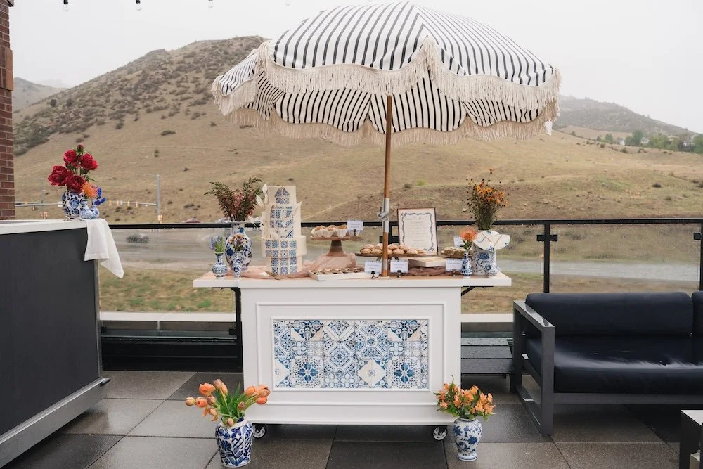 Portuguese-styled dessert cart set on a rain rooftop balcony, adorned with florals