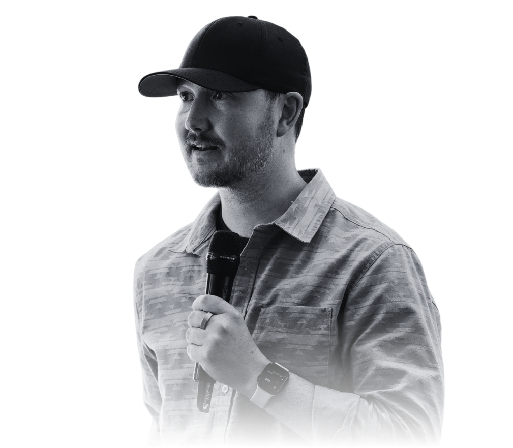 Man wearing a black baseball cap and striped shirt speaking into a microphone