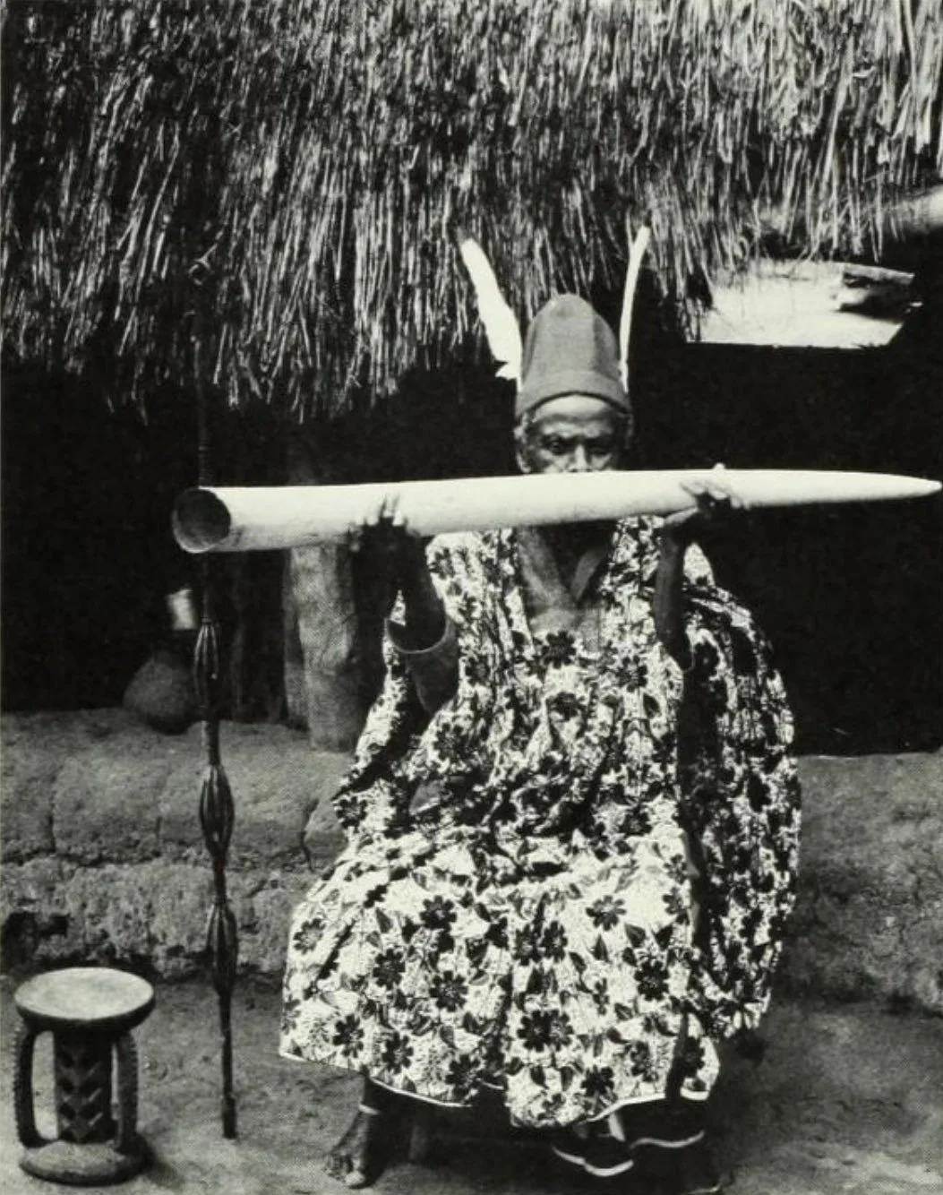 Ozo title bearer from Ebenebe, featuring an elephant tusk trumpet, a stool, and a staff, 1966.