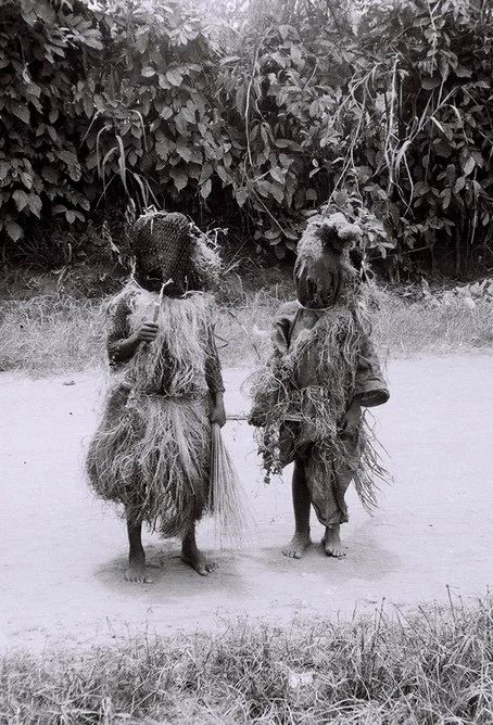 Young Igbo Mask Dancers Wearing Net Masks and Raffia Costumes.