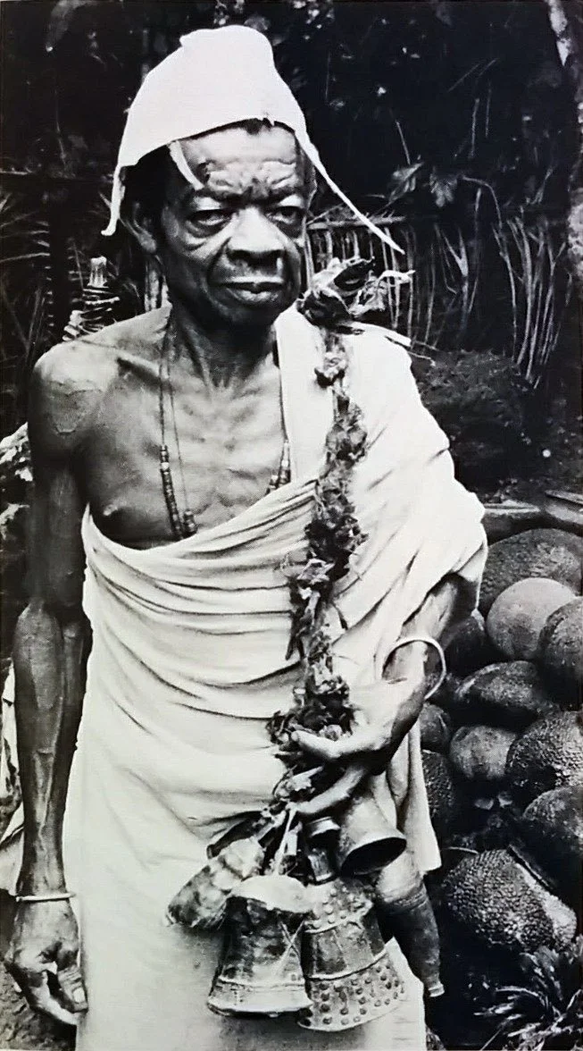 Atama (Priest) of the Ide Shrine in Ugbene Ovoro (Nsukka area) holding seven ancient bronze bells. 📸: Herbert Cole in 1983.