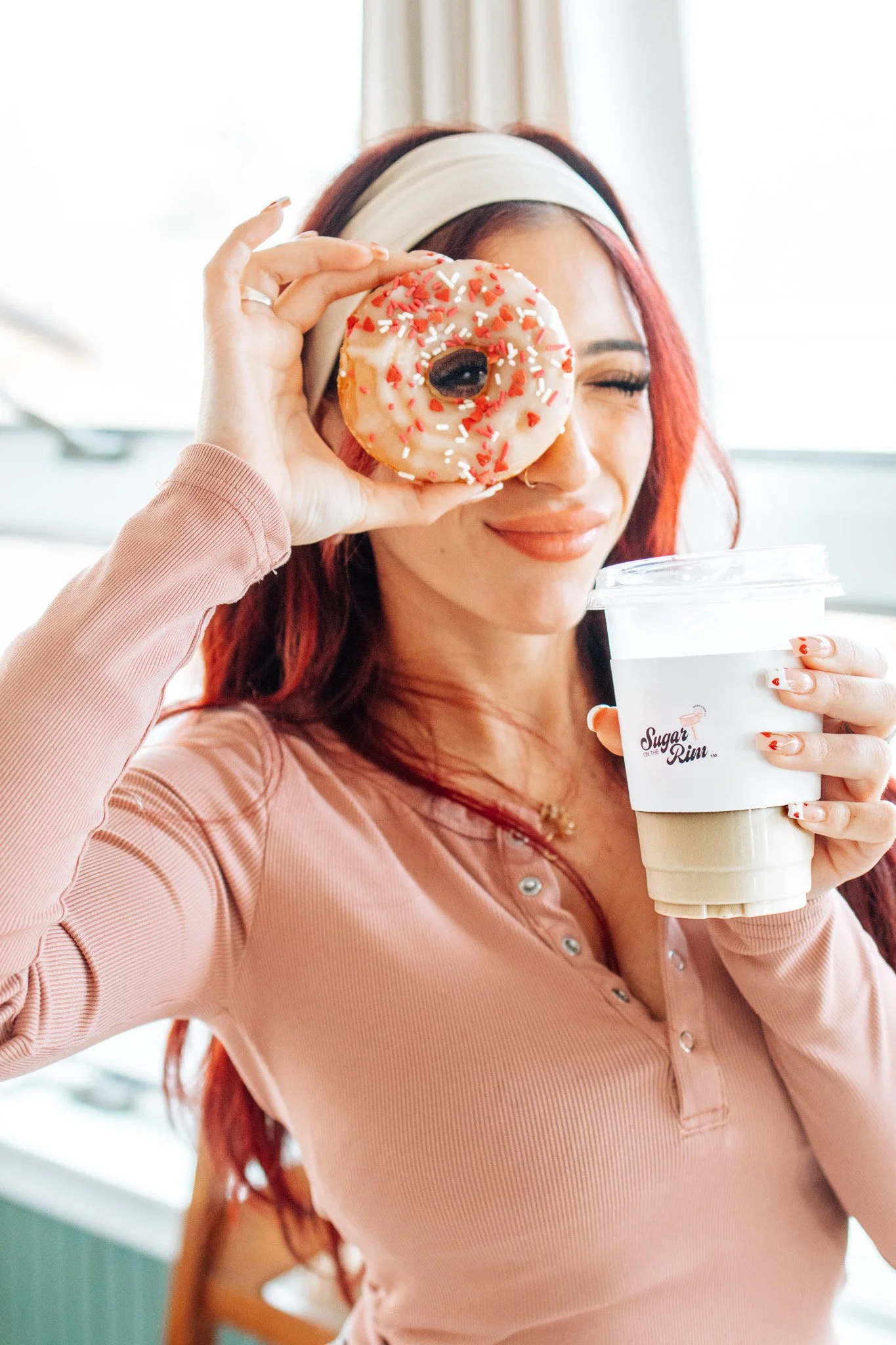 Elegant table setting with white plates, silver cutlery, pink roses, candles, and decorative cushions.