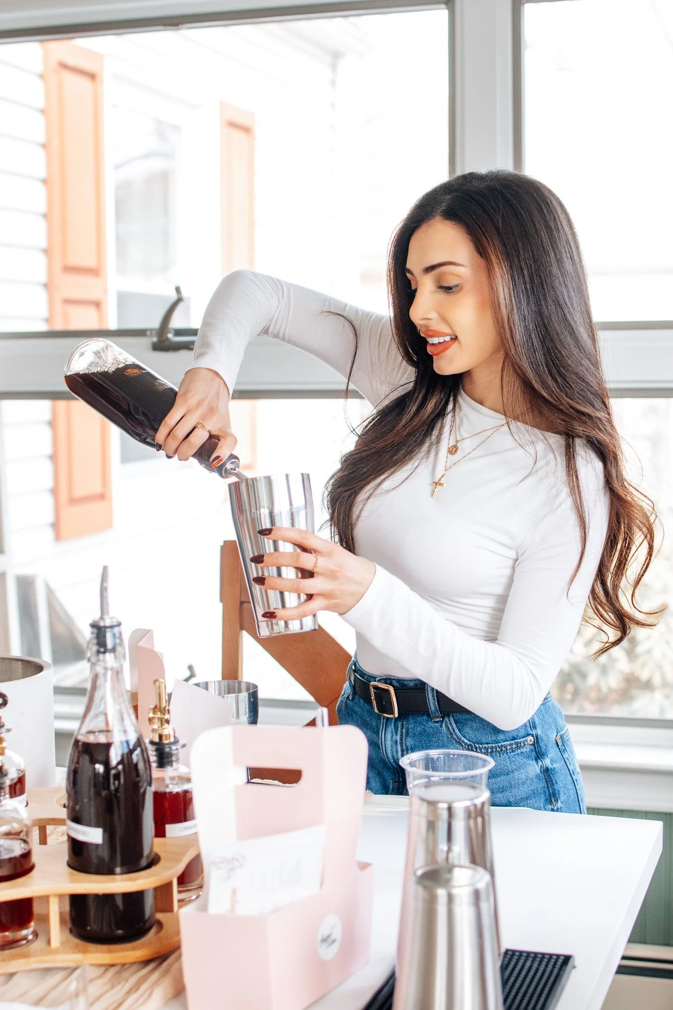 Four women in pajamas drinking cocktails and smiling, with a holiday wreath in the background.