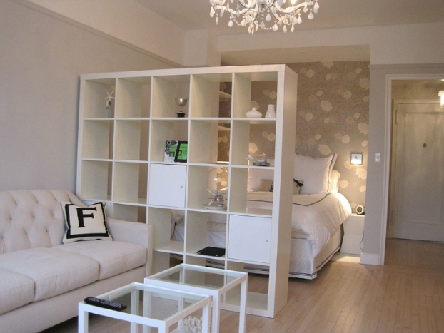 This person cleverly used wallpaper and an open shelving unit to zone a bedroom space.