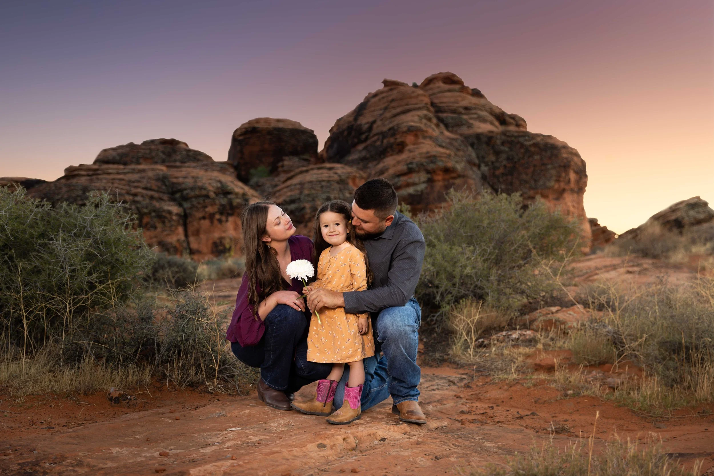 Young family posing together a Cougar Cliffs in Snow Canyon State park in Southern Utah. Cinematic Destination family photographer!