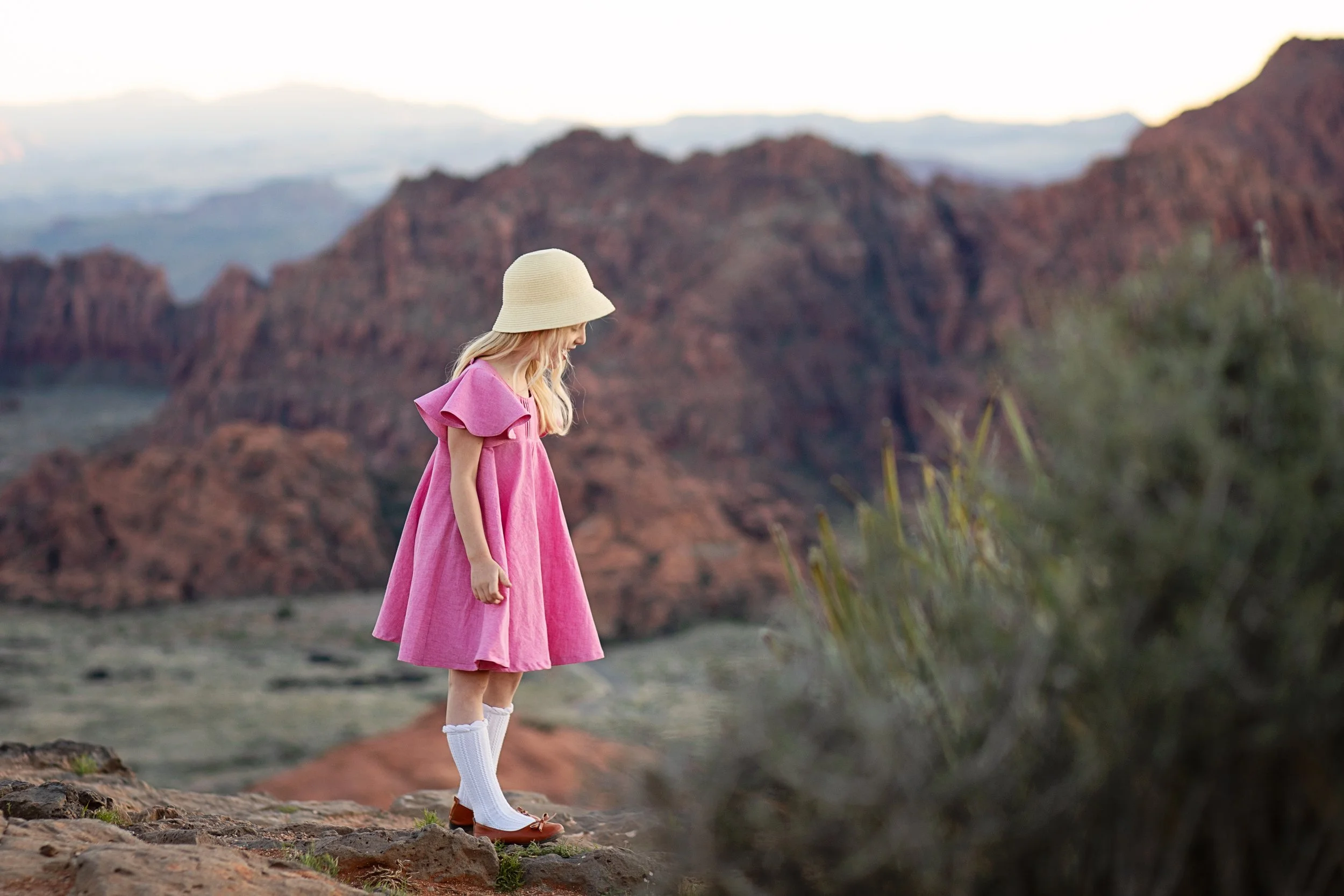 Girl in pink dress agains the red rocks of southern utah