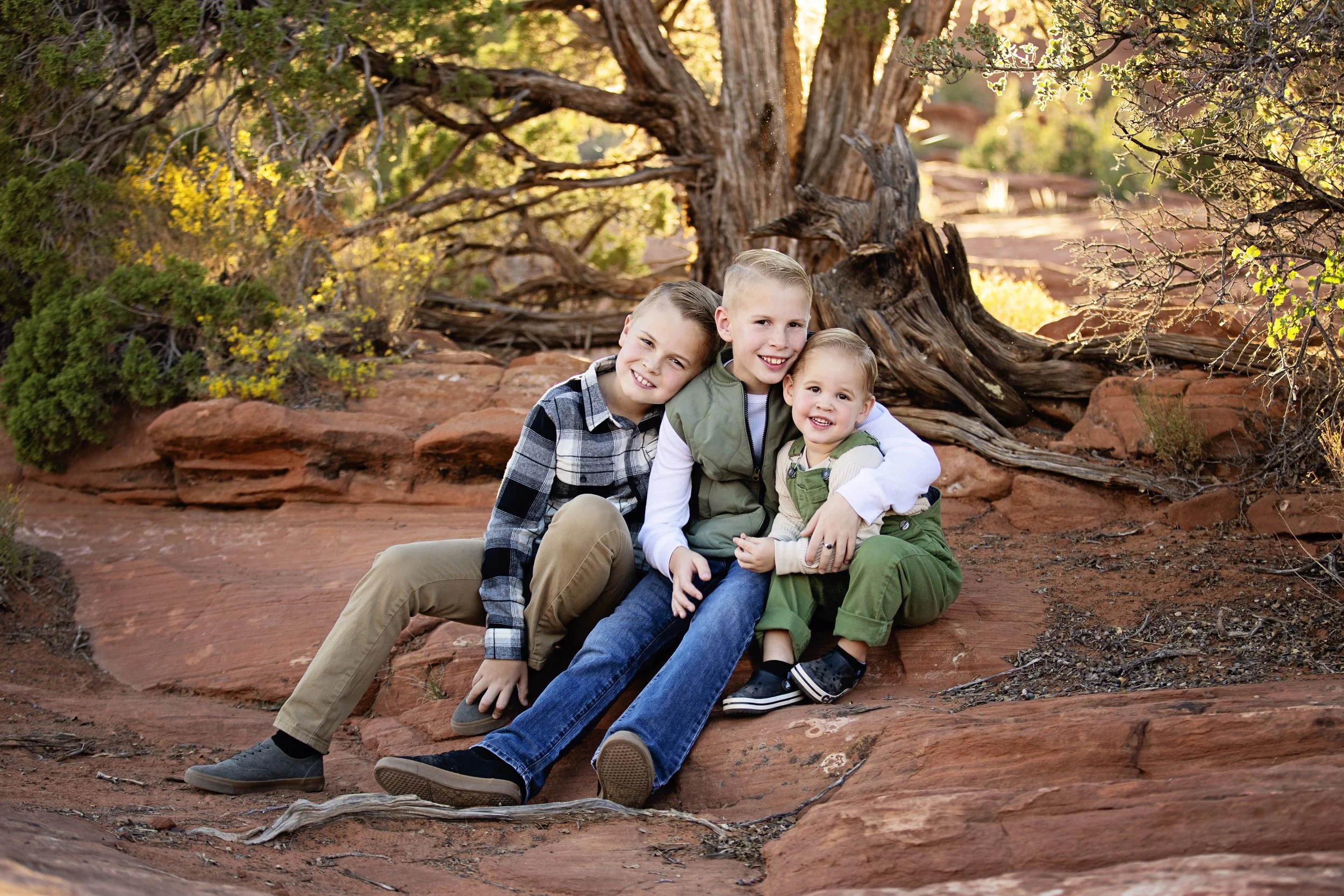 Three bothers hugging wearing shades of green durning cinematic family portraits in Southern Utah near Zion National Park