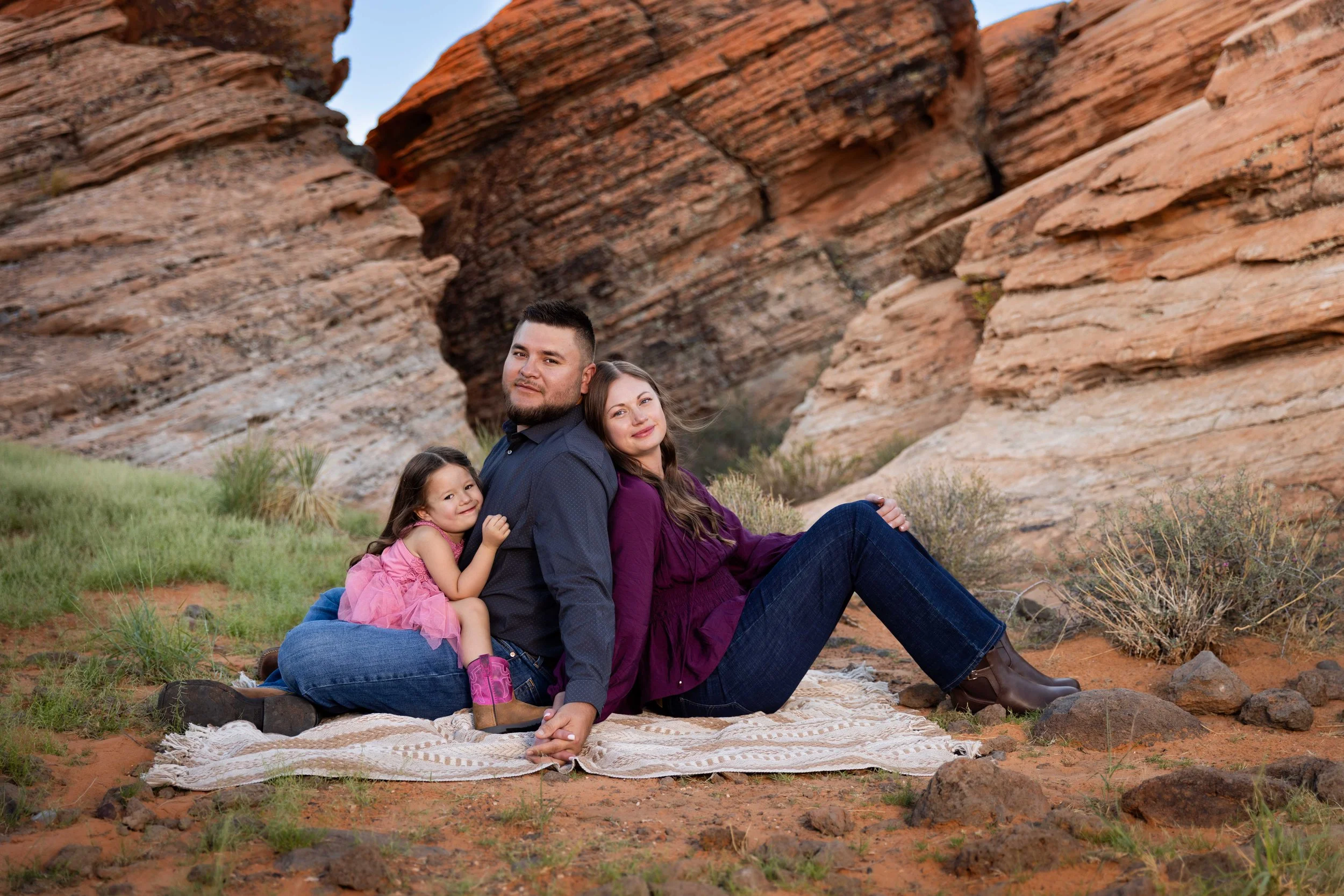 Young Family sitting on blanket back to back amongst the coral sand stone of Cougar Cliffs near Snow Canyon in Southern Utah