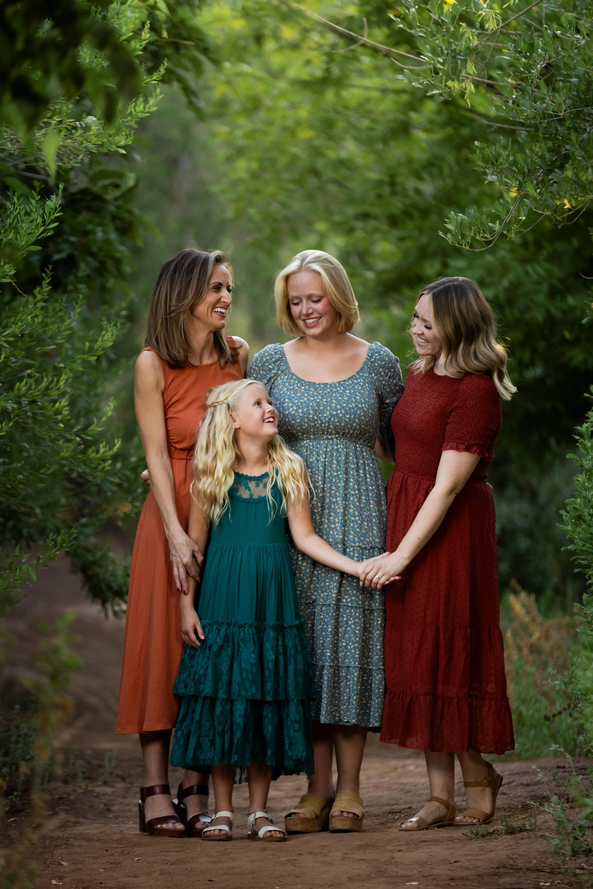 a mother with her daughters smiling at each other during their family photo session in Saint George Utah.