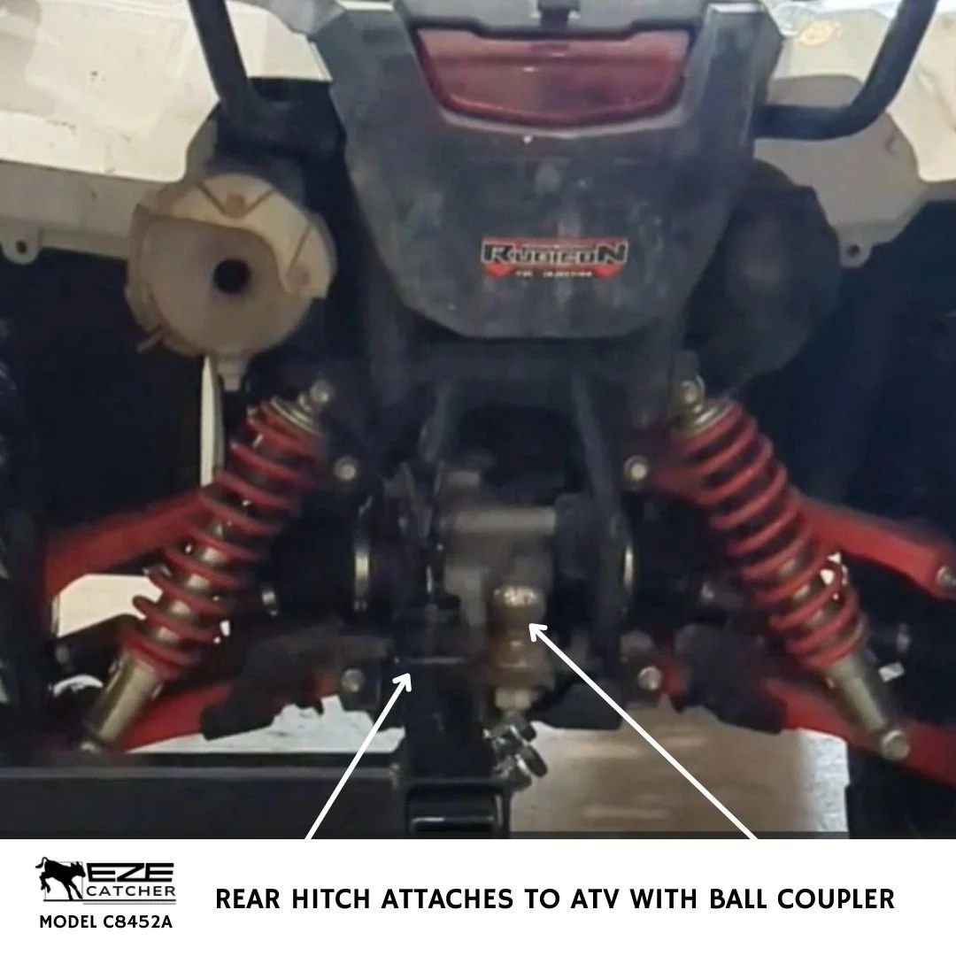 A white ATV, quad vehicle parked in a shop that is attached with a front rack mounting system to a green EZE-Catcher calf catching cage.
