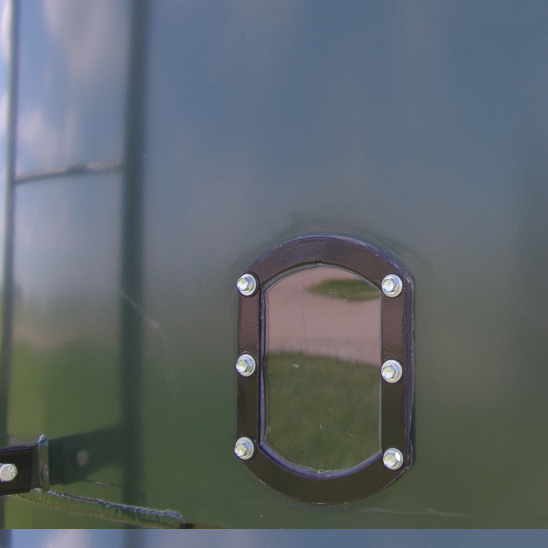 Sight glass with a black frame bolted on a green cattle feeder