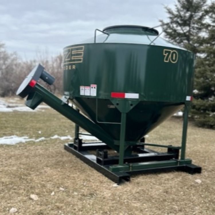 70 bushel eze-feeder sitting in a field with dry grass and patches of snow .