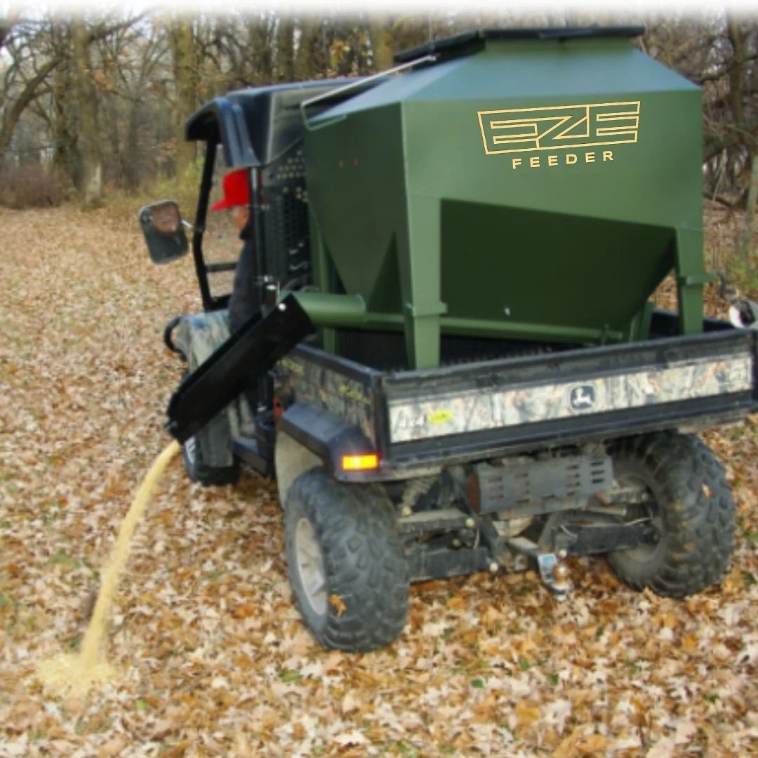 UTV feeder in the back of a UTV with the driver discharging feed from the cab of the utv, in a foresty area with fall leaves on the ground