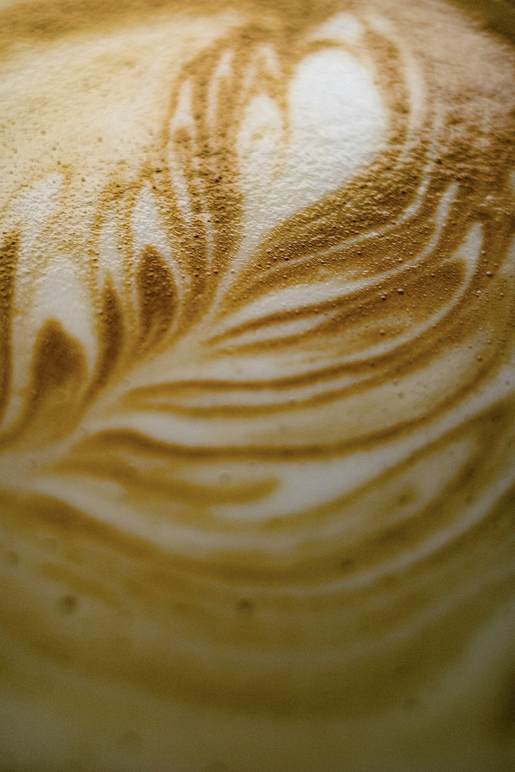 Close-up of coffee foam with latte art in a leaf pattern.