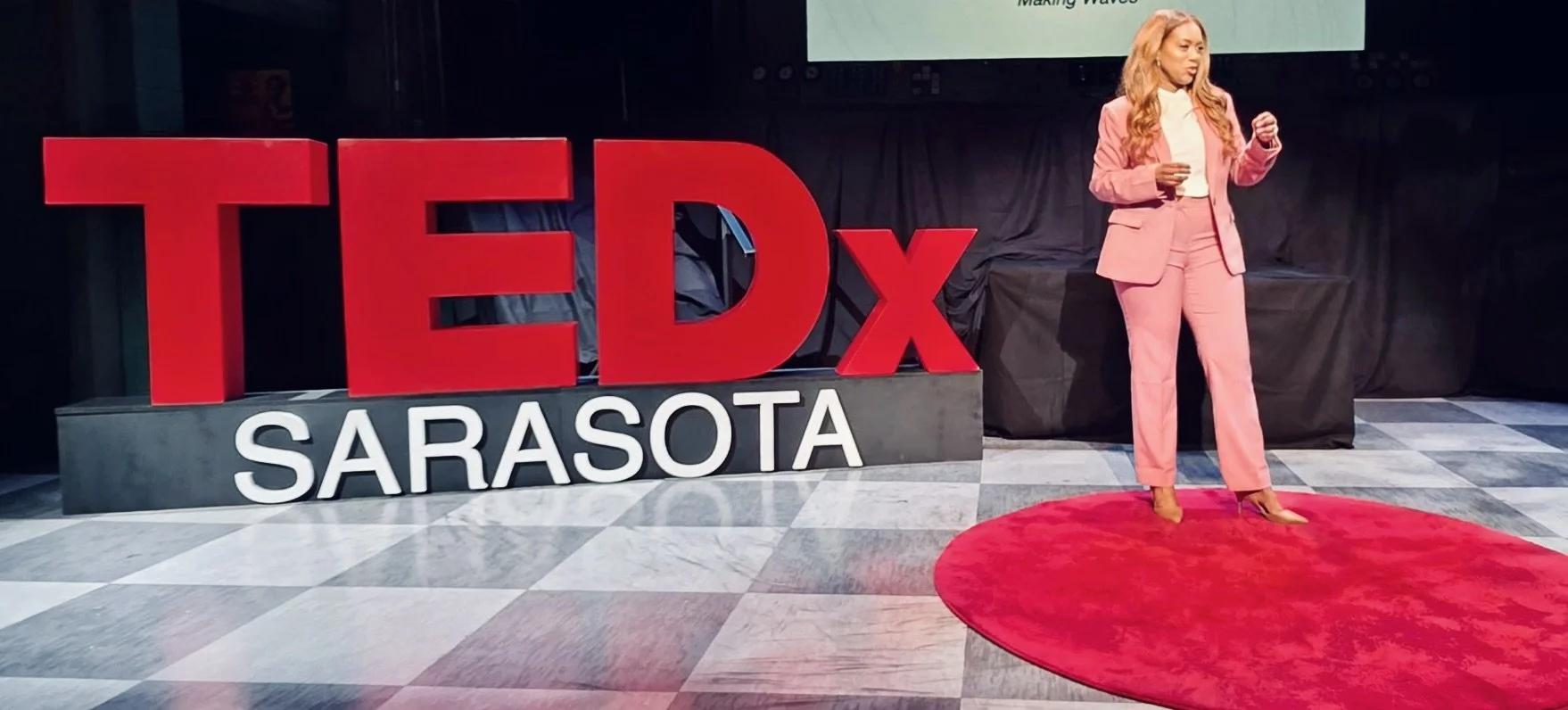 Dr. Rene Roberts standing on the red circle at TEDx Sarasota 2026.