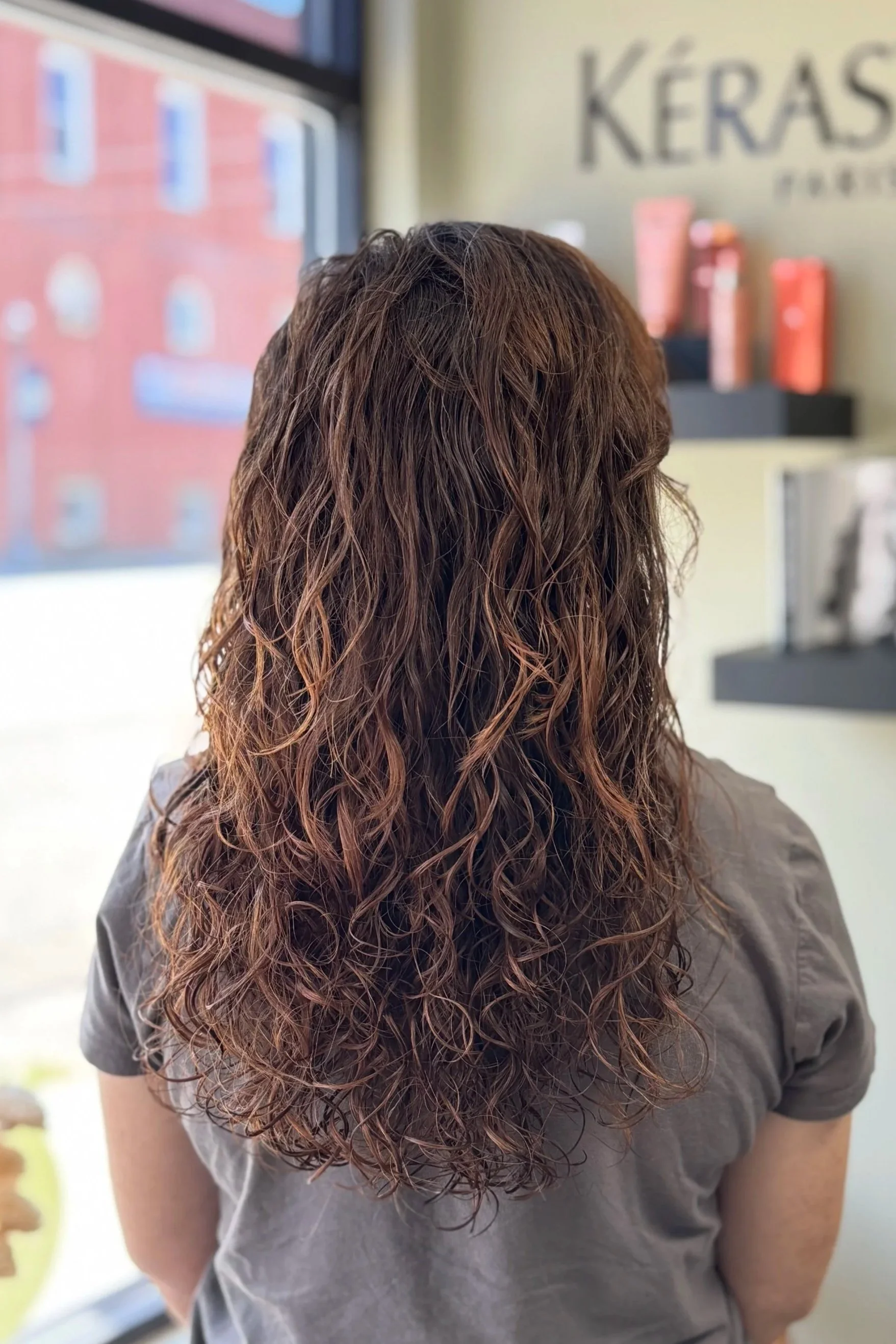A woman with long brunette naturally curly hair styled