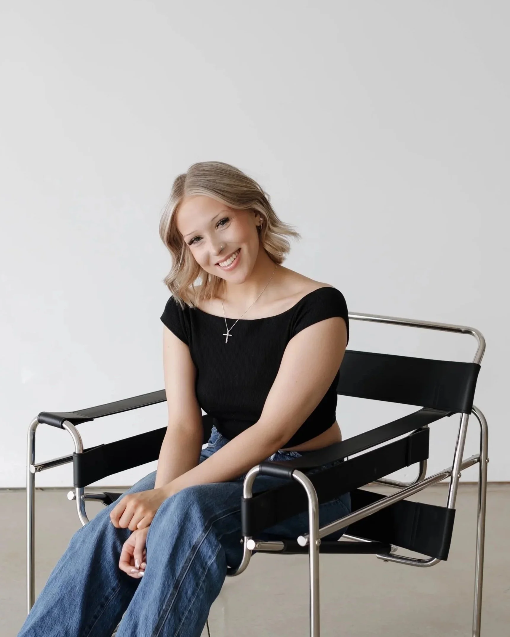 Jess - stylist sitting in black chair smiling