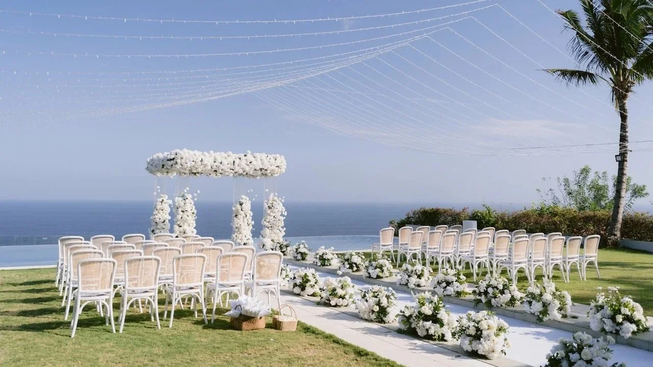 Karen and Tommy’s clifftop wedding ceremony at The Surga Villa Estate, Uluwatu, Bali, with white florals and ocean views