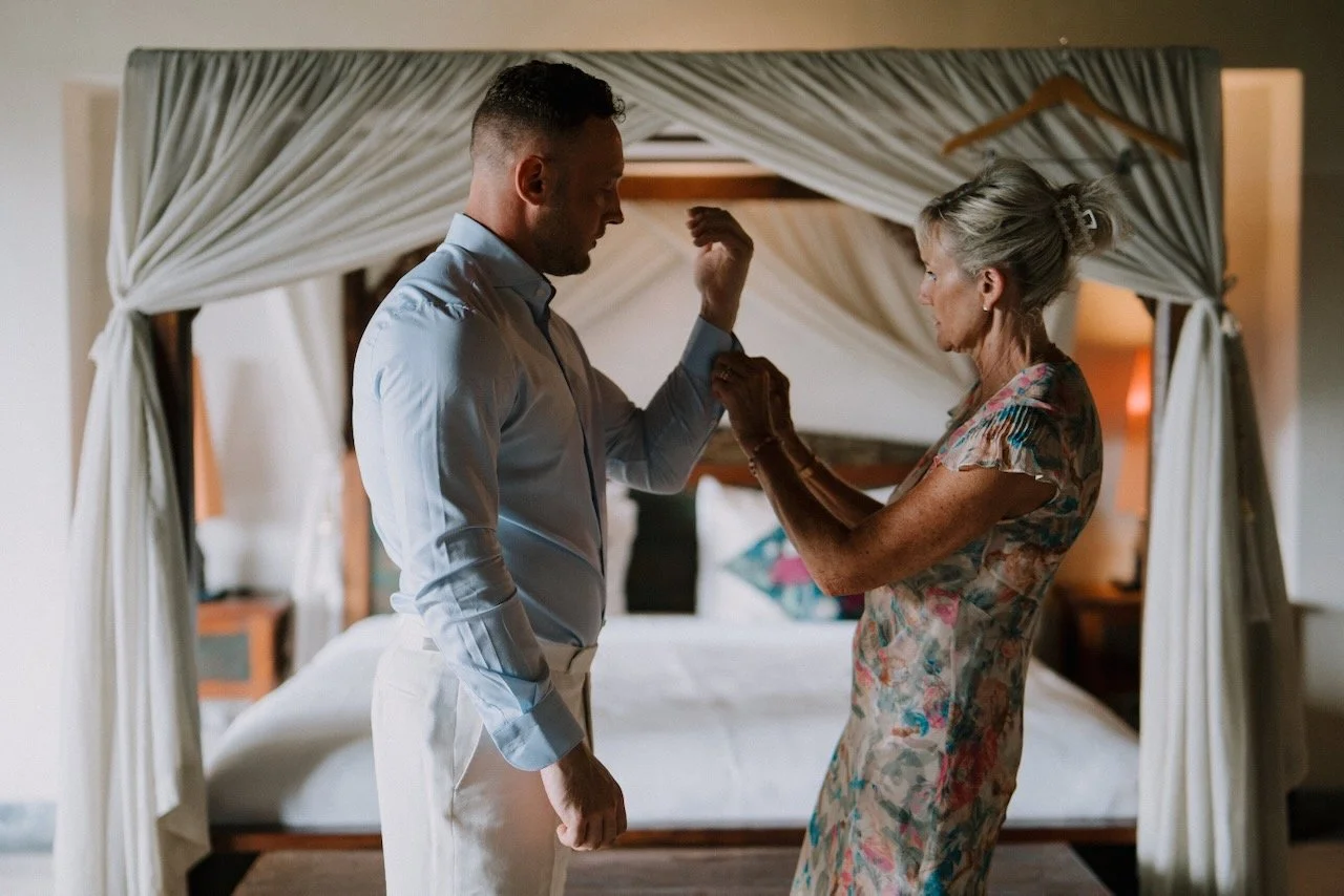 Groom getting ready with his mother adjusting his cuff at luxury Bali villa before the wedding ceremony.