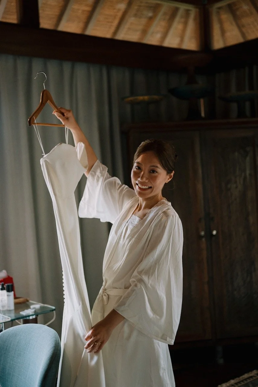 Bride holding her minimalist white wedding dress while getting ready in Bali luxury accommodation.