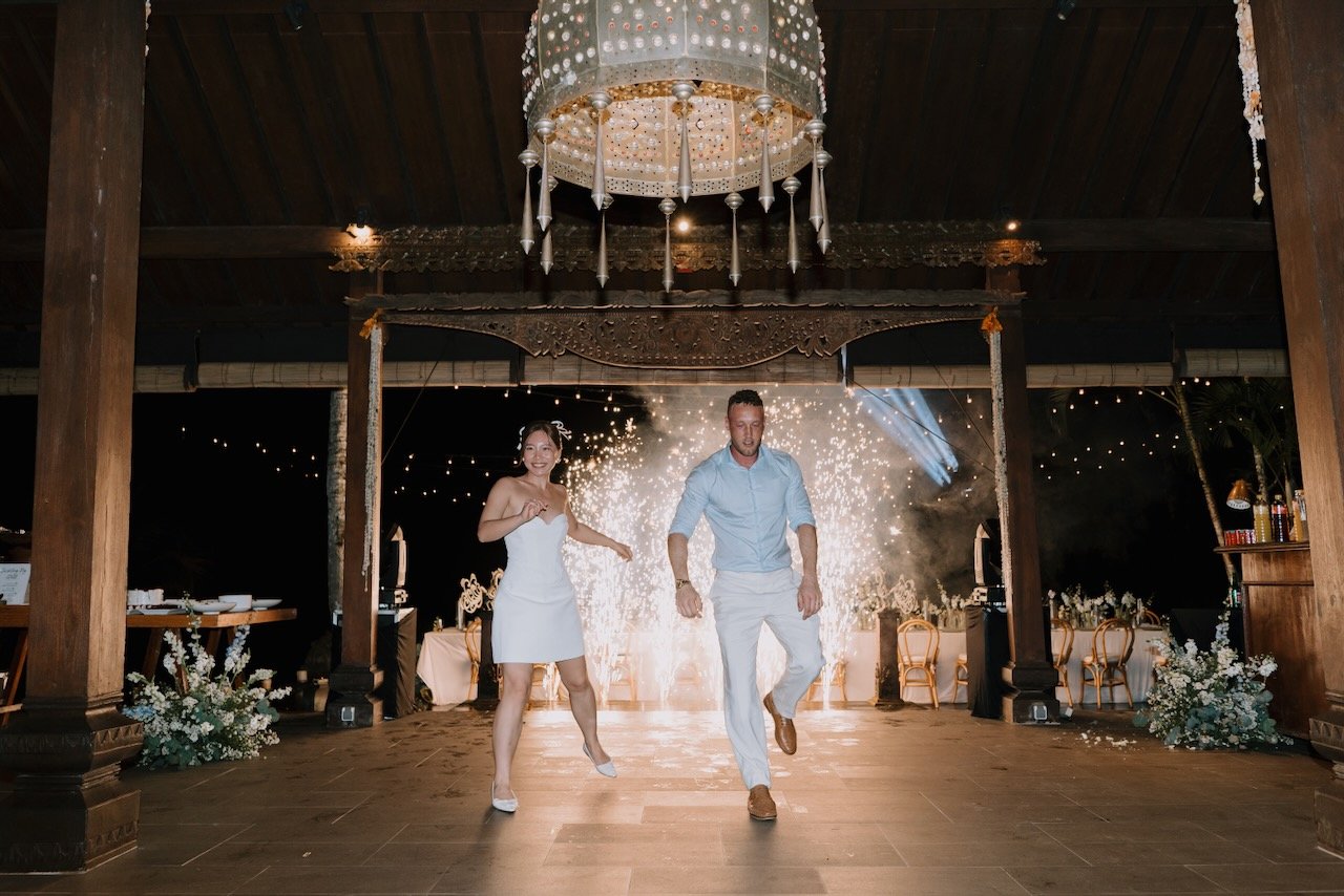 Bride and groom dancing with sparkling effects at evening Bali wedding reception celebration.