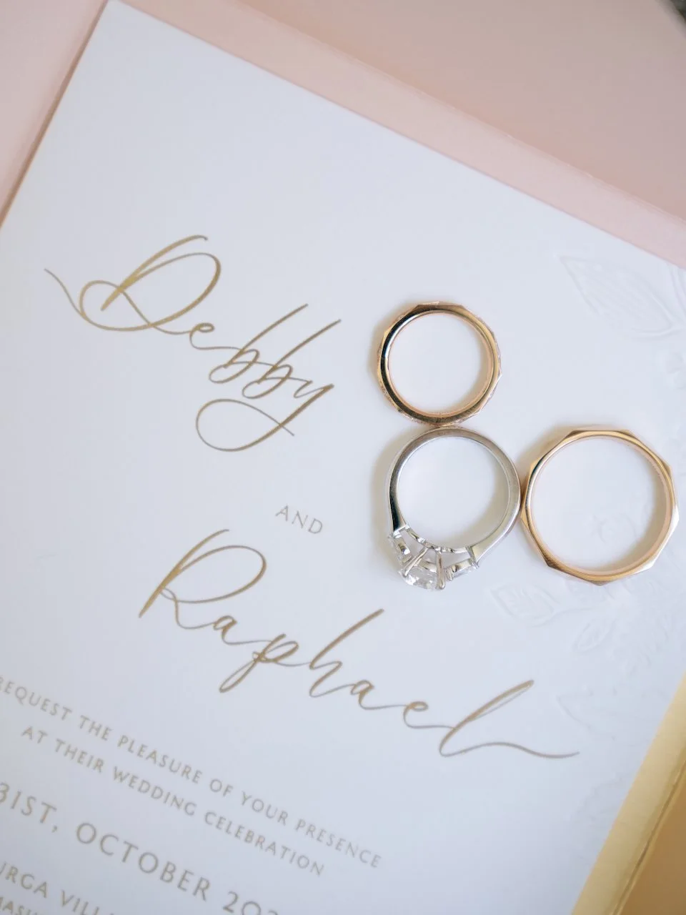 Elegant wedding rings resting on a personalised invitation suite, photographed as refined Bali wedding flat lay details.