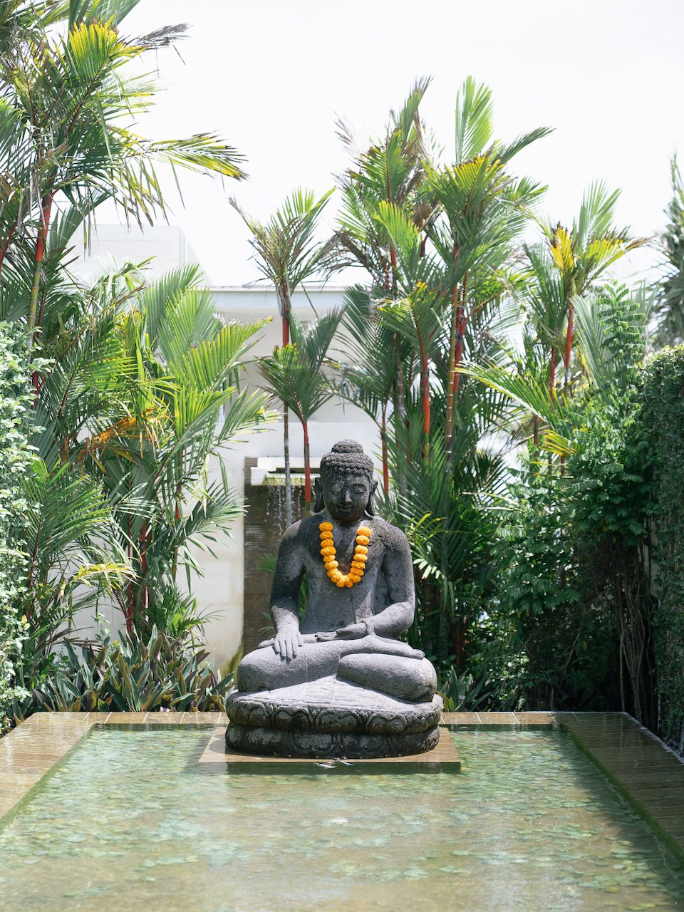 Serene stone Buddha statue surrounded by tropical greenery at a luxury Bali wedding villa ceremony setting.