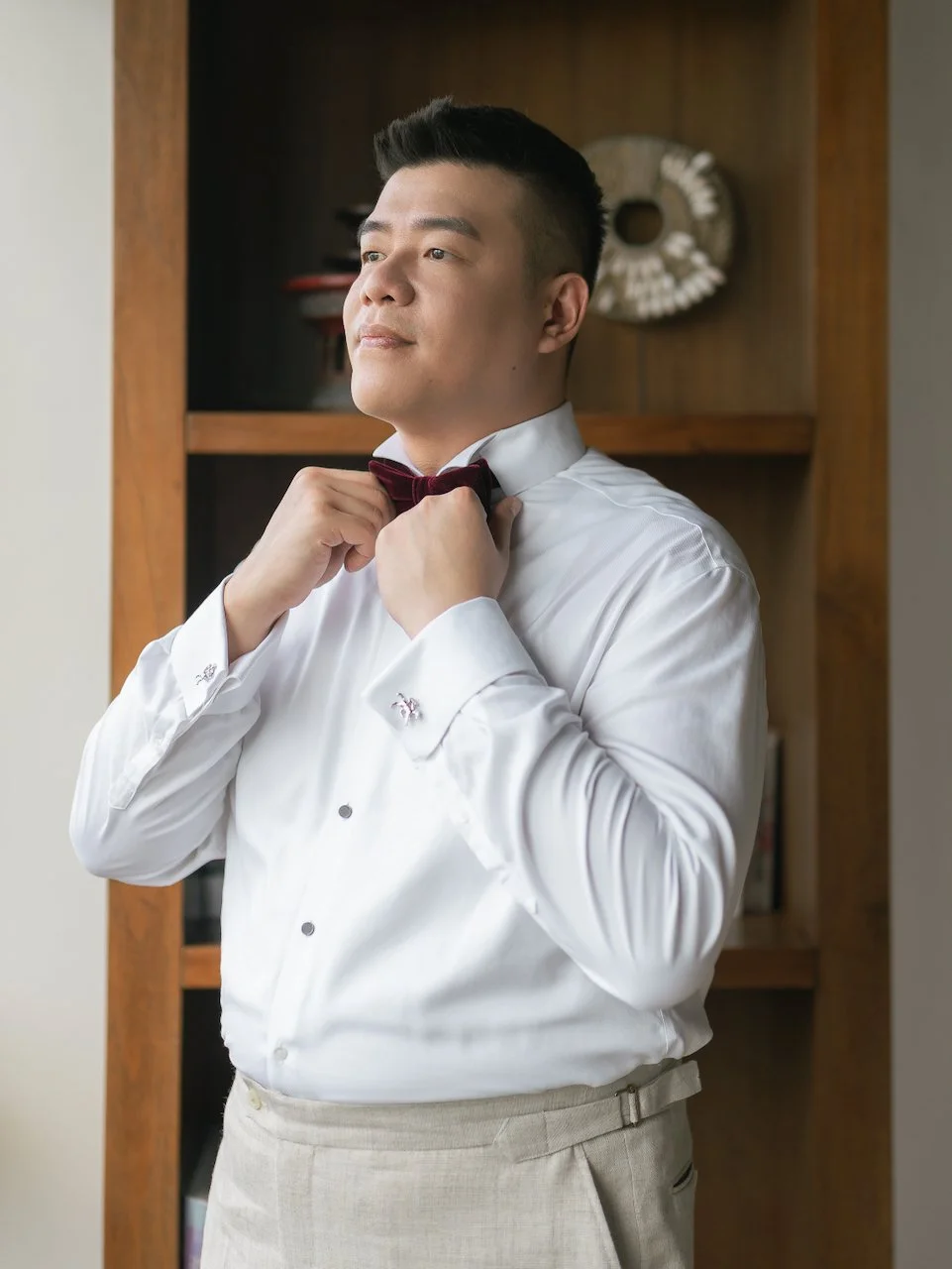Groom adjusting his bow tie during morning preparations at a Bali destination wedding villa.