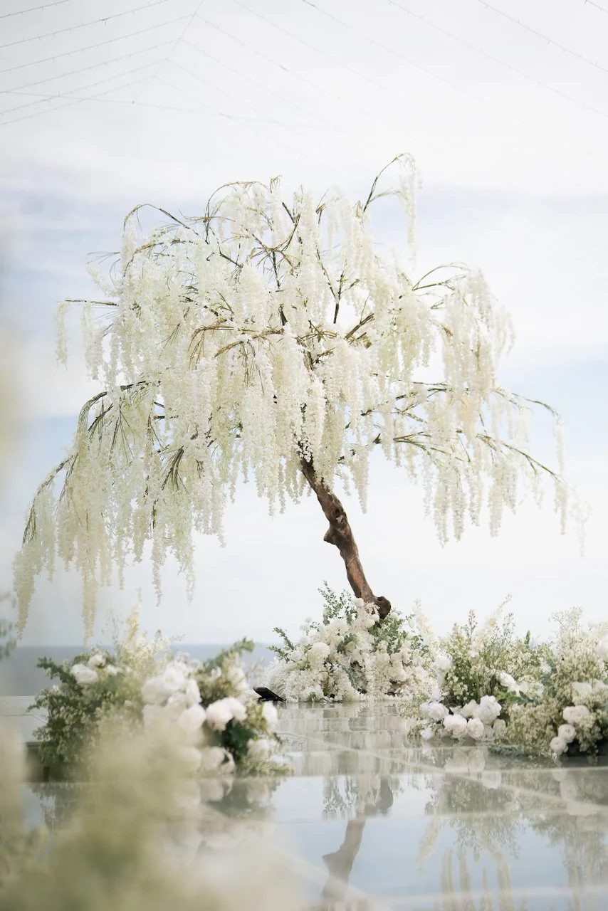 Statement floral ceremony installation with cascading white blooms overlooking the ocean at a Bali wedding venue.