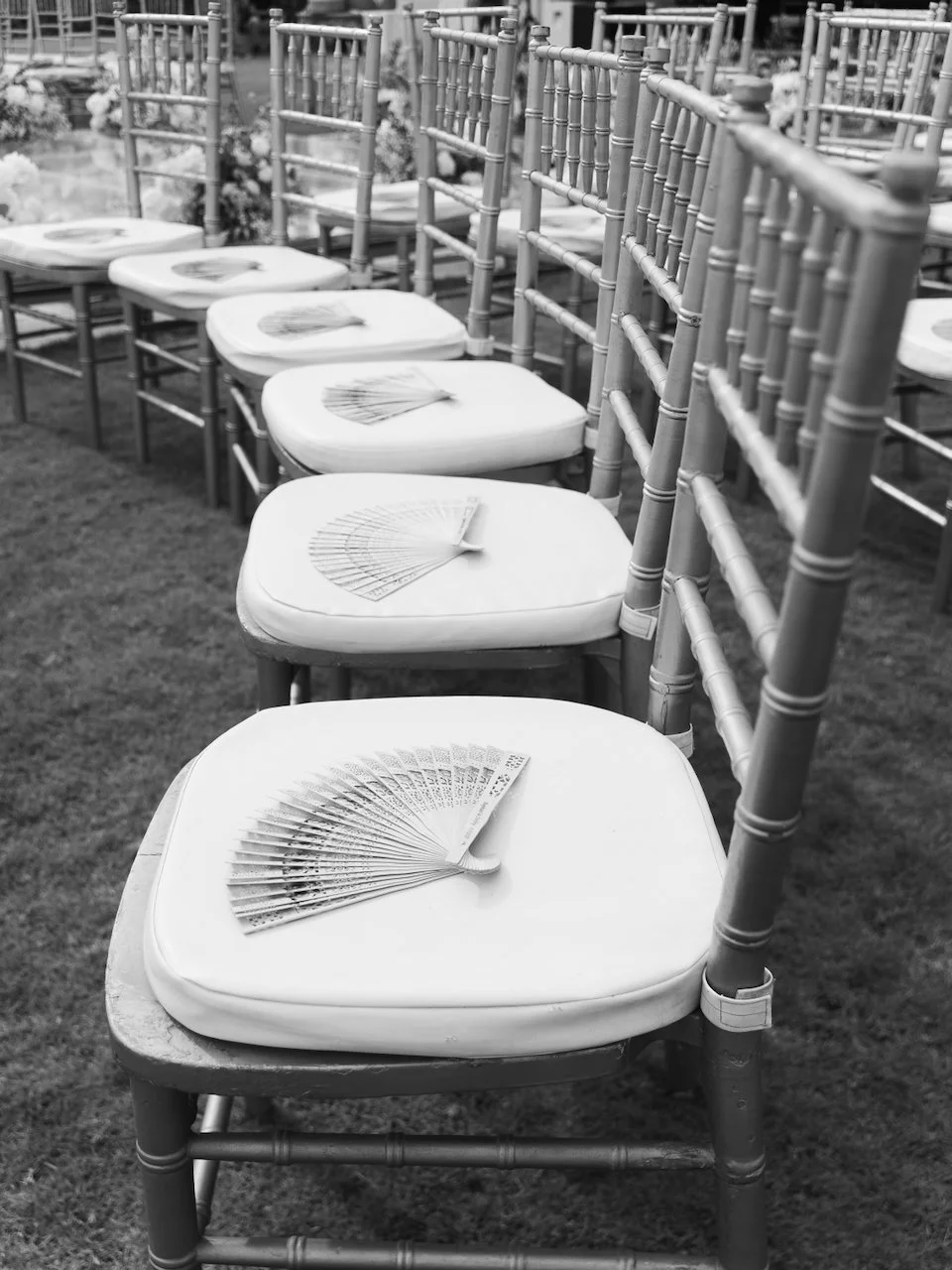 Ceremony chairs lined with handheld fans, styled for a chic outdoor Bali destination wedding.