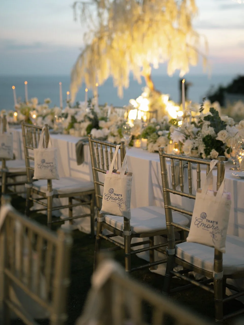 Romantic sunset wedding reception table with candlelight, white florals and ocean views in Bali.