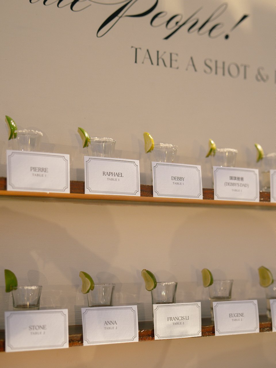 Wedding escort card display with personalised shot glasses and modern signage at a Bali destination wedding.