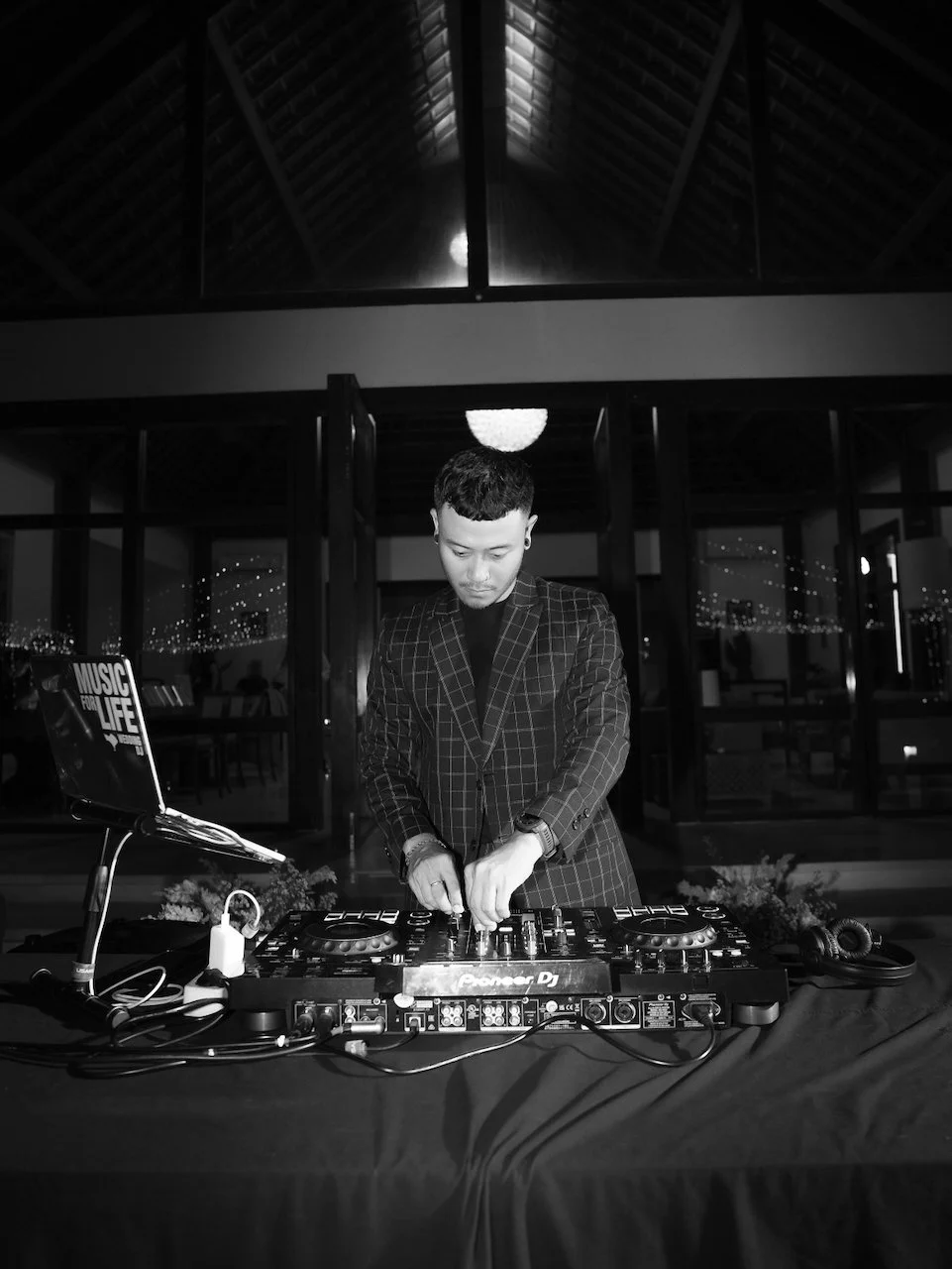 Wedding DJ performing during an evening Bali destination wedding reception beneath an open-air pavilion.