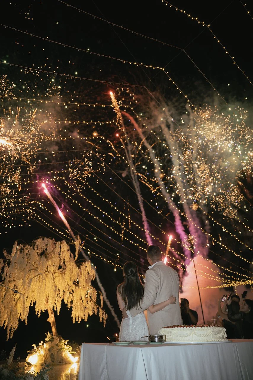 Fireworks lighting up the night sky above a luxury Bali wedding reception with fairy lights and floral décor.