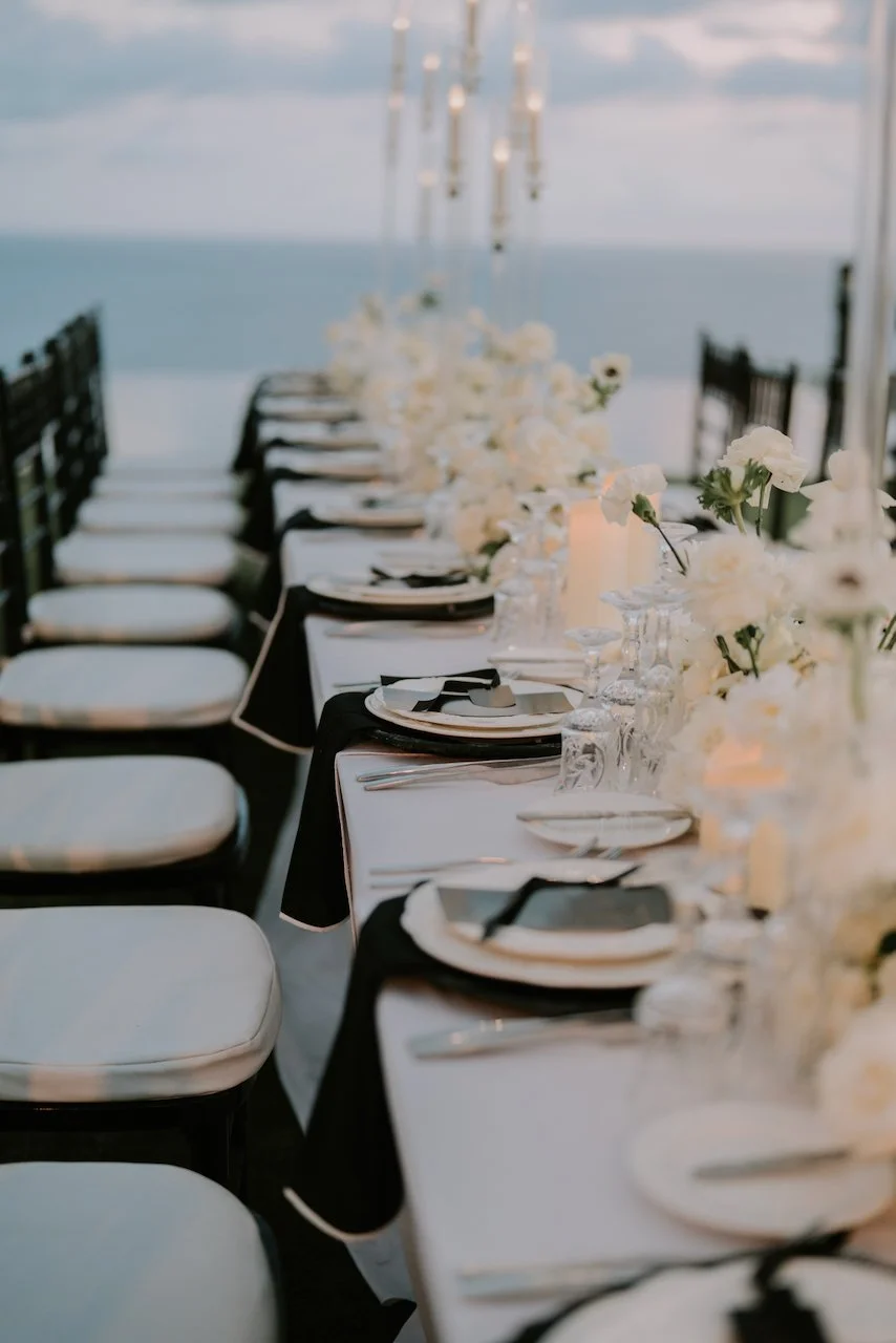 Elegant long-table reception setup with white florals, candles and ocean views at a luxury Bali wedding reception