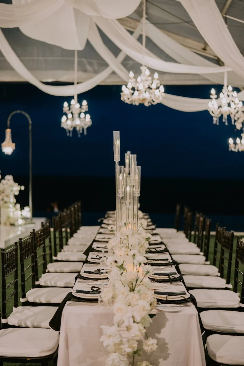 Symmetrical long-table reception design with white flowers and chandeliers at a luxury Bali wedding