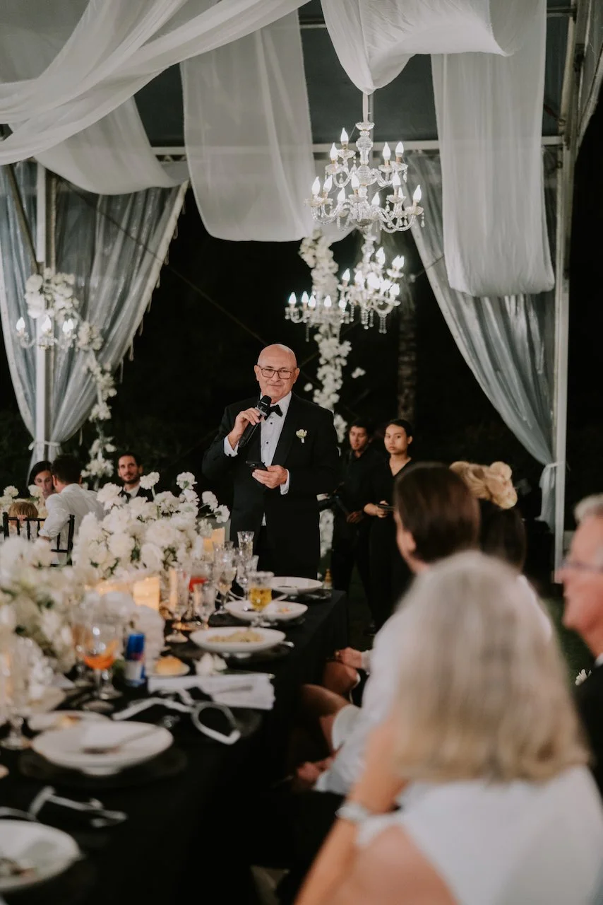 Wedding speech delivered during the candlelit reception beneath draped fabric and chandeliers in Bali