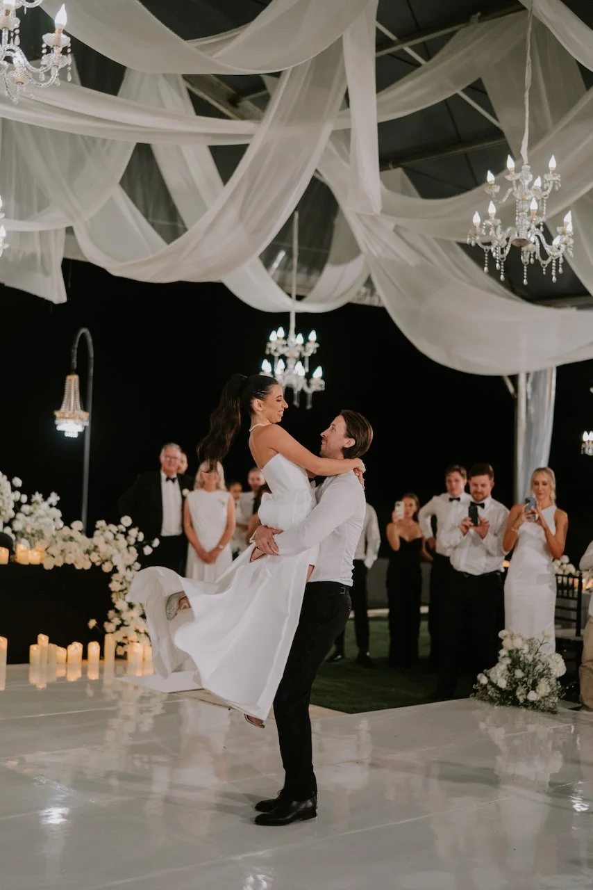 Groom lifting the bride during a joyful dance moment at their evening wedding reception in Bali