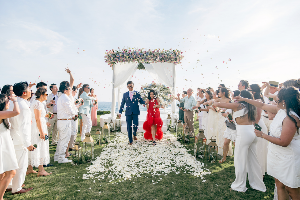 Guests throwing petals at the newlyweds walking down a coastal wedding aisle in Bali